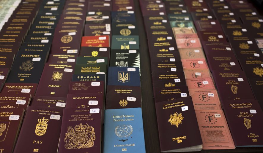 In this Wednesday, Feb. 28, 2018 photo Greek authorities present confiscated passports and identification cards at the Athens Police Headquarters. Last year, Greek police caught a total of 1,672 migrants trying to sneak out of the country by plane. There's a thriving illegal industry in Greece that churns out counterfeit passports and identity papers. (AP Photo/Petros Giannakouris)