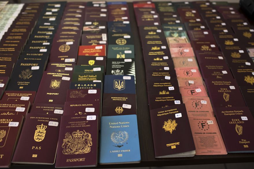 In this Wednesday, Feb. 28, 2018 photo Greek authorities present confiscated passports and identification cards at the Athens Police Headquarters. Last year, Greek police caught a total of 1,672 migrants trying to sneak out of the country by plane. There's a thriving illegal industry in Greece that churns out counterfeit passports and identity papers. (AP Photo/Petros Giannakouris)