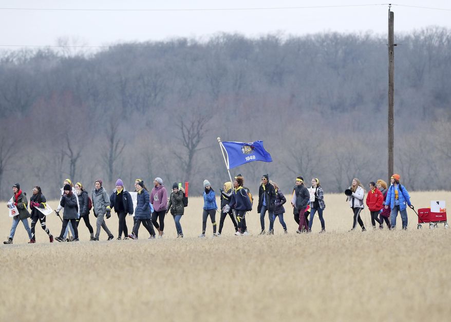 A group of about 40 students make their way along Old Highway 92 south of Evansville, Wis., on Tuesday, March 27, 2018, as they march to U.S. Rep. Paul Ryan's hometown of Janesville to call for stricter gun control laws. An end-of-march event is scheduled at Traxler Park in Janesville on Wednesday, March 28 at noon. (Anthony Wahl/The Janesville Gazette via AP)