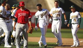 Oakland Athletics&#39; Marcus Semien, center, celebrates with Matt Olson (28) and Jake Smolinski (5) after driving in the winning run in the the 11th inning of a baseball game against the Los Angeles Angels on Thursday, March 29, 2018, in Oakland, Calif. (AP Photo/Ben Margot)