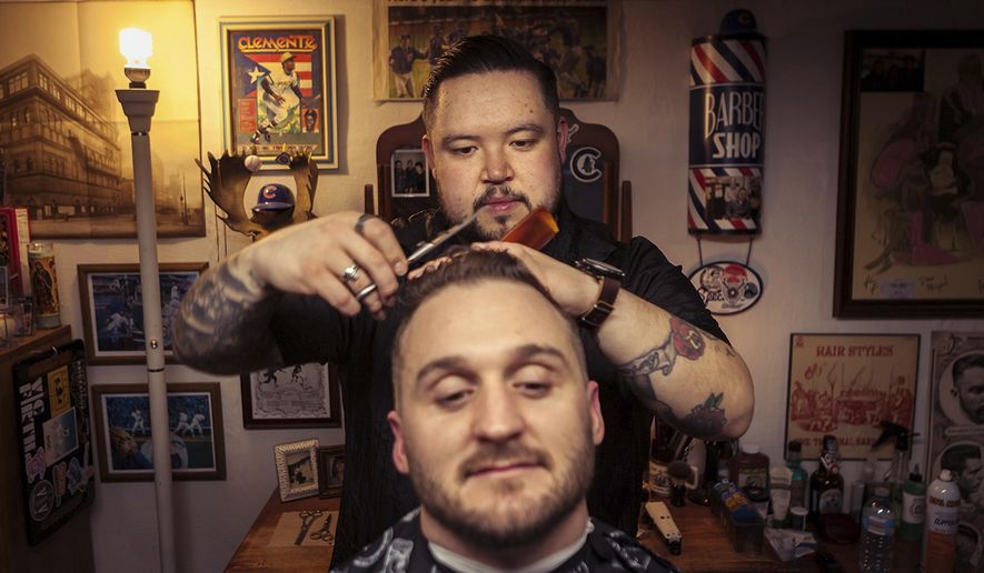 In this March 2018 photo, Barber Lupe Carroll, cuts Rende Langlos' hair in the basement of Carroll's home in Bourbonnais, Ill. Carroll who competed in Season 5 of "The Voice," recently became a licensed barber. If a man's basement could tell his story, this basement says everything about Carroll. The 31-year-old Bourbonnais resident gained national attention when he competed in Season 5 of "The Voice" in 2013. But the tattooed man who gained prominence for his acoustic cover of "If I Were a Carpenter" now is cutting his way into another career. (John Dykstra/The Daily Journal via AP)