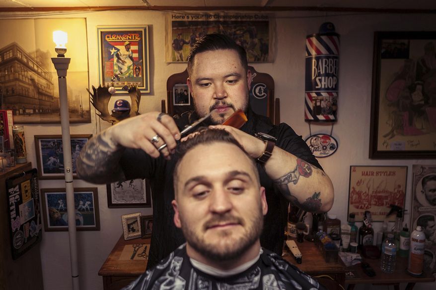 In this March 2018 photo, Barber Lupe Carroll, cuts Rende Langlos' hair in the basement of Carroll's home in Bourbonnais, Ill. Carroll who competed in Season 5 of "The Voice," recently became a licensed barber. If a man's basement could tell his story, this basement says everything about Carroll. The 31-year-old Bourbonnais resident gained national attention when he competed in Season 5 of "The Voice" in 2013. But the tattooed man who gained prominence for his acoustic cover of "If I Were a Carpenter" now is cutting his way into another career. (John Dykstra/The Daily Journal via AP)