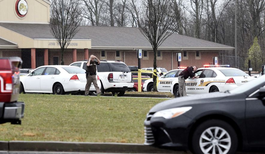 In this Wednesday, March 28, 2018 photo, law enforcement officers work at the scene of a shooting involving multiple officers from multiple agencies in the back parking lot of John Hardin High School in Radcliff, Ky. The school went on lockdown and no students were in immediate danger. (Jill Pickett /The News-Enterprise via AP)
