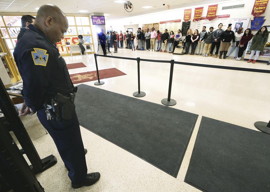 In this March 14, 2018, file photo, police patrolman John Burgette, 53, a school resource officer for 18 years, bows his head as Scranton High School students stand in silence to protest gun violence for 17 minutes at the high school in Scranton, Pa. (Butch Comegys/The Times-Tribune via AP) ** FILE **