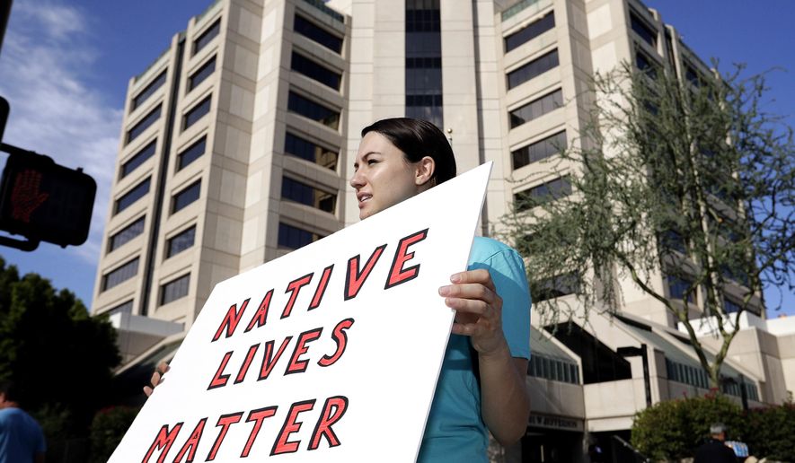 FILE - In this July 25, 2016, file photo, Heather Hamel protests outside Maricopa County Attorney Bill Montgomery's office, in Phoenix. The Navajo Nation has sued the federal government and the city of Winslow, Ariz., over the death of a scissors-wielding tribal member shot by a police officer for the northern Arizona city. (AP Photo/Matt York, file)