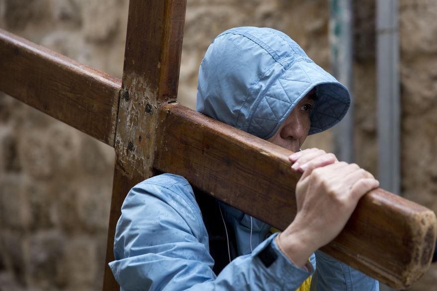 A Christian worshipper holds a cross as he walks along the Via Dolorosa toward the Church of the Holy Sepulchre, traditionally believed by many to be the site of the crucifixion of Jesus Christ, during the Good Friday procession in Jerusalem&#39;s Old City. (AP Photo/Ariel Schalit) ** FILE **