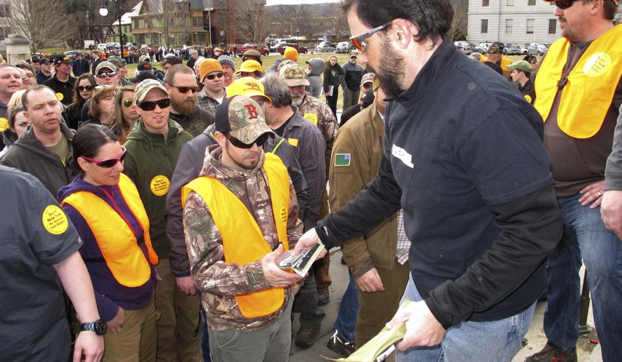 Rob Curtis, executive editor of a firearms magazine, hands out 30-round magazines at a gun rights event outside the Vermont Statehouse in Montpelier, Vt., on Saturday, March 31, 2018, to oppose gun restriction legislation passed by the Legislature the previous day. (AP Photo/Lisa Rathke)