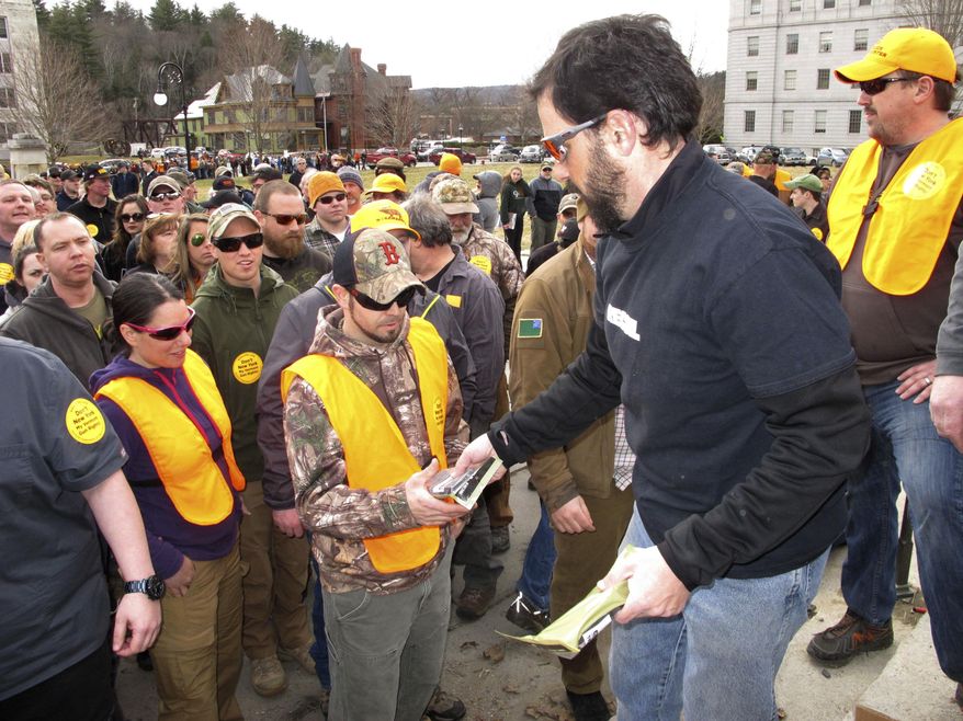 Rob Curtis, executive editor of a firearms magazine, hands out 30-round magazines at a gun rights event outside the Vermont Statehouse in Montpelier, Vt., on Saturday, March 31, 2018, to oppose gun restriction legislation passed by the Legislature the previous day. (AP Photo/Lisa Rathke)