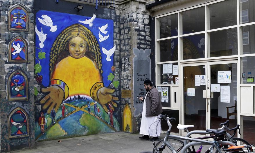 In this photo taken in Friday, March 23, 2018, Farooq, who declined to give his last name looks at his phone as he waits outside a medial surgery in London. To track down refugees in Britain who may have broken immigration rules, the government is controversially turning to the doctors who treat them for information, although data sharing could make migrants nervous about getting medical attention. (AP Photo/Alastair Grant)