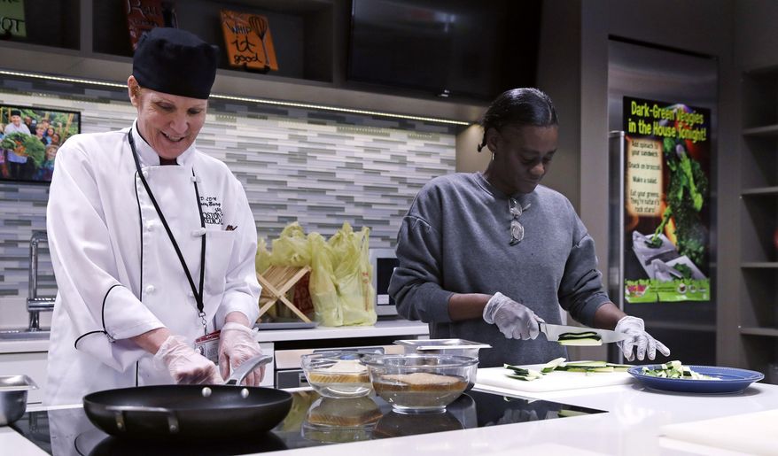 In this Thursday, March 15, 2018, photo, registered dietician Tracey Burg, the head chef of The Teaching Kitchen, left, and Felicha Young prepare a meal during a "Cooking for Recovery" class at the Boston Medical Center in Boston. The hospital offers the class to patients in recovery, including Young, as part of a growing trend toward taking a more comprehensive approach to treating addiction. (AP Photo/Charles Krupa)