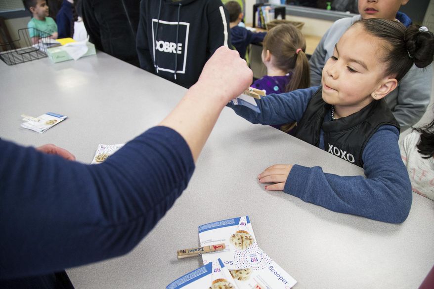 Kindergartener Jasmin Hernandez receives a prize and her "clip-up" pin after being called to the office during morning announcements at McKinley Elementary School in Yakima, Wash., Tuesday, March 20, 2018. The program is part of the schools efforts to address behavior issues in students who have experienced trauma. (Shawn Gust/Yakima Herald-Republic via AP)