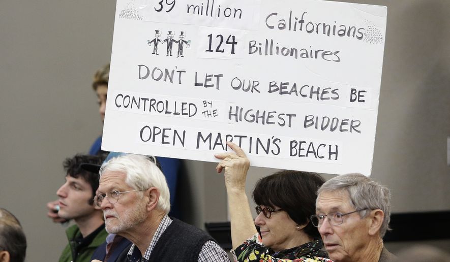 Julie Graves, a supporter of public access to Martin&#x27;s Beach, displays a sign during a meeting of the State Lands Commission, in Sacramento, Calif., Tuesday, Dec. 6, 2016. After negotiating for a year with the property owner, Vinod Khosla, the co-founder of Sun Microsystems Inc., in an attempt to find a solution to allow the public access to the beach, the commission decided to begin exploring whether to use eminent domain to seize the property. (AP Photo/Rich Pedroncelli)