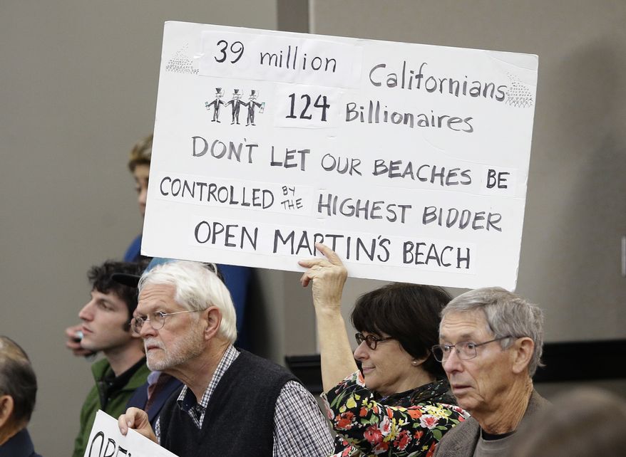 Julie Graves, a supporter of public access to Martin&#39;s Beach, displays a sign during a meeting of the State Lands Commission, in Sacramento, Calif., Tuesday, Dec. 6, 2016. After negotiating for a year with the property owner, Vinod Khosla, the co-founder of Sun Microsystems Inc., in an attempt to find a solution to allow the public access to the beach, the commission decided to begin exploring whether to use eminent domain to seize the property. (AP Photo/Rich Pedroncelli)