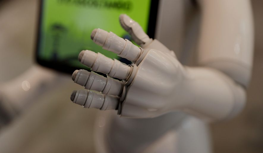 In this photo dated March 12, 2018, robot Robby Pepper&#39;s hand is seen in the foreground as it welcomes guests at the front desk of hotel in Peschiera del Garda, northern Italy. Robby Pepper, billed as Italy&#39;s first robot concierge, has been programed to answer simple guest questions in Italian, English and German, the humanoid, speaking robot will be deployed all season at a hotel on the popular Garda Lake to help relieve the desk staff of simple, repetitive questions. (AP Photo/Luca Bruno)