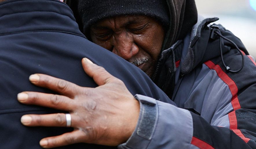 In this Sunday, April 1, 2018, photo, Eli Boyd Sr., a local resident, cries on a family member in Jackson, Mich., after a shooting. Authorities say a man has died and a police officer was wounded in a leg following an exchange of gunfire in southern Michigan. The shooting happened Sunday afternoon in Jackson after police were called to respond to a report of a domestic assault. (Jack Zellweger/The Ann Arbor News via AP)