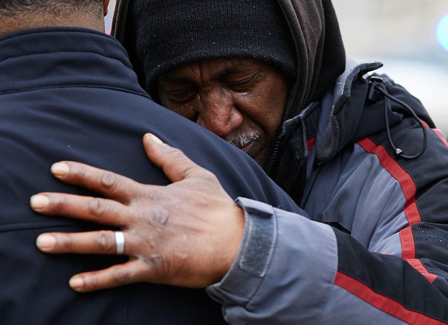 In this Sunday, April 1, 2018, photo, Eli Boyd Sr., a local resident, cries on a family member in Jackson, Mich., after a shooting. Authorities say a man has died and a police officer was wounded in a leg following an exchange of gunfire in southern Michigan. The shooting happened Sunday afternoon in Jackson after police were called to respond to a report of a domestic assault. (Jack Zellweger/The Ann Arbor News via AP)