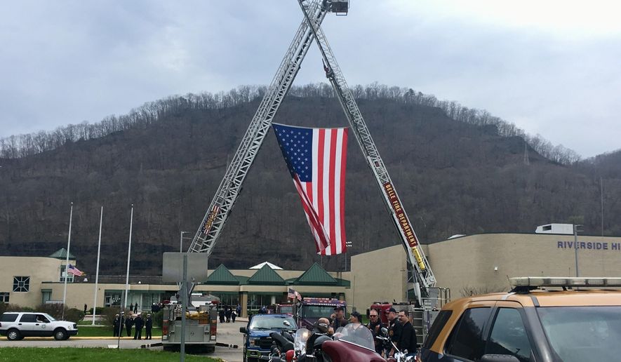 Fire ladder trucks are shown outside Riverside High School during the funeral for Pratt Volunteer Fire Department Lt. Tom Craigo in Belle, W.Va., Tuesday, April 3, 2018. Services have been held for the West Virginia firefighter whose firetruck slammed into a rock wall while responding to a fatal accident. (AP Photo/John Raby)