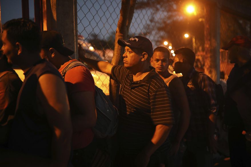 Central American migrants stand in line for food during the annual Migrant Stations of the Cross caravan or "Via crucis," organized by the "Pueblo Sin Fronteras" activist group, as the caravan makes a few-days stop at a sports center in Matias Romero, Oaxaca state, Mexico, late Monday, April 2, 2018. The annual caravans have been held in southern Mexico for years as an Easter-season protest against the kidnappings, extortion, beatings and killings suffered by many Central American migrants as they cross Mexico. (AP Photo/Felix Marquez)