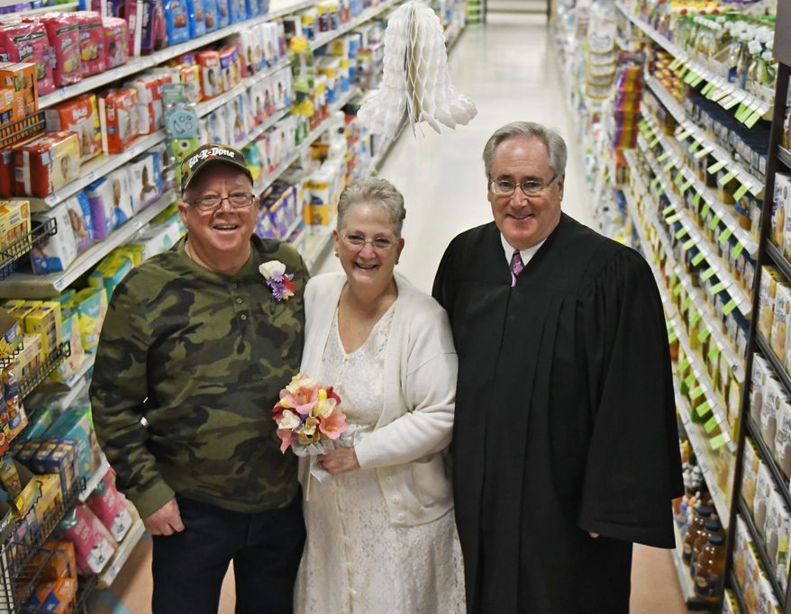 In this April 1, 2018 photo, Larry Spiering and Becky Smith pose for a photo where they held their wedding ceremony officiated by District Judge Frank Pallone on Easter Sunday in aisle 13 of the Community Market in Lower Burrell, Pa. Smith said she was working at the supermarket when Spiering walked up and gave her a piece of paper with his name and phone number on it. She said it was only fitting that they married in the aisle where they met. (Jack Fordyce/Pittsburgh Tribune-Review via AP)
