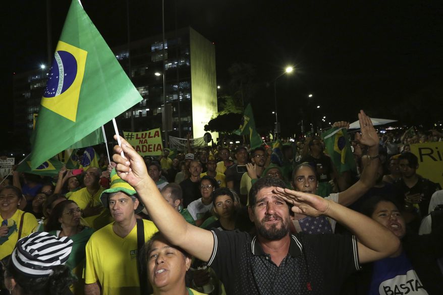 Demonstrators against Brazil's former President Luiz Inacio Lula da Silva watch as Supreme Court justices' votes are made public outside the National Congress in Brasilia, Brazil, Wednesday, April 4, 2018. Brazil's top court is voting on whether da Silva can stay out of prison while appealing a corruption conviction, a decision that could radically alter October's presidential election in Latin America's largest nation. (AP Photo/Eraldo Peres)