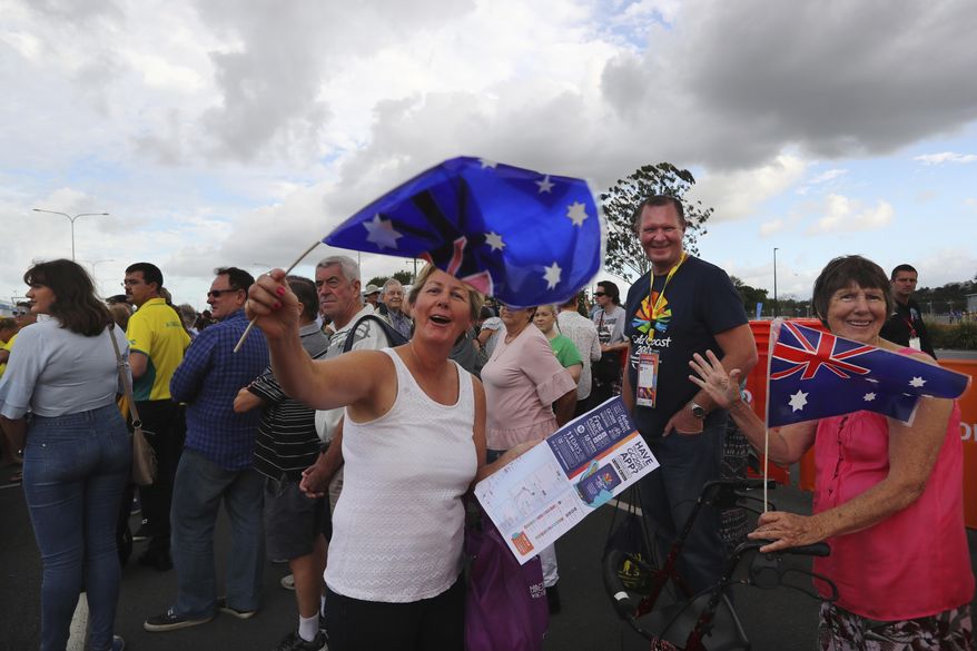 Australian women wave their country flags as they wait in a queue to enter the Carrara Stadium for the opening ceremony of the Commonwealth Games in Gold Coast, Australia, Wednesday, April 4, 2018. (AP Photo/Manish Swarup)