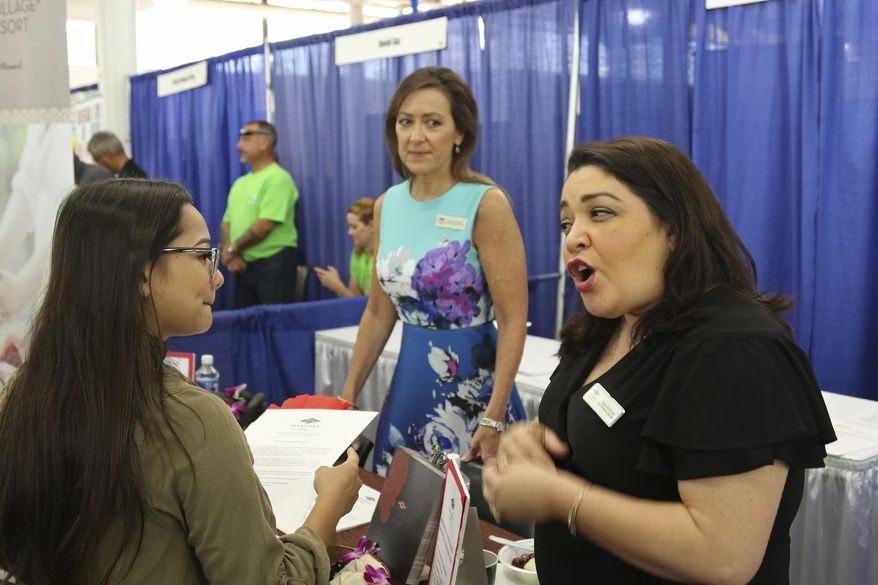 In this March 28, 2018, photo, Roxy Creed, left, speaks to Mandara Spa Operations Manager Lena Andrade about employment opportunities at a job fair in Honolulu. Recently released numbers show Hawaii boasts the United States' lowest jobless rate, at 2.1 percent. But experts say the figure is masking underlying problems. (AP Photo/Audrey McAvoy)