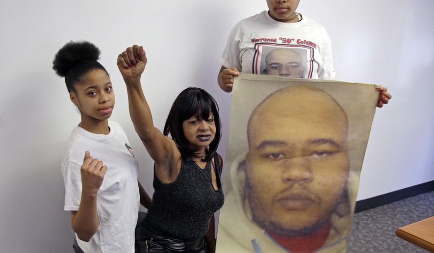 Hope Coleman raises her fist as she poses with her granddaughters, Danina, left, and Destiny, holding a photo of her son, Terrence, Wednesday, April 4, 2018, at a law office in Boston. Coleman filed a federal lawsuit Wednesday accusing the city of failing to properly train officers on how to deal with mentally ill people. Terrence Coleman, who is mentally ill, was killed in 2016 after his mother called 911 for an ambulance to take him to the hospital. (AP Photo/Elise Amendola)