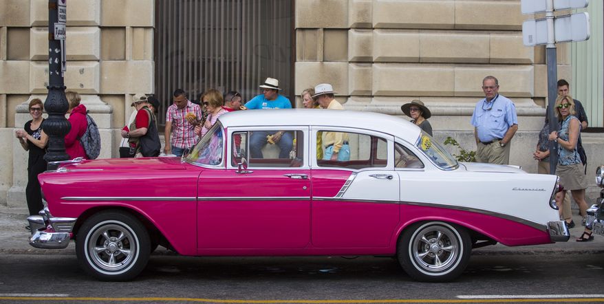 FILE - In this Feb. 22, 2016, file photo, tourists look at a classic American car parked beside the cruise ship terminal in Havana, Cuba. Cuba is one of four destinations where a new trip-planning company called ViaHero is offering its services. For a flat fee of $25 a day, a ViaHero expert on the ground in your destination plans your trip, from lodging and airport pick-up to what to see and where to eat. The service combines authentic local recommendations, the convenience of online booking and the old-school guidance of a travel agent. In addition to Cuba, ViaHero plans trips in Iceland, Japan and Colombia. (AP Photo/Desmond Boylan, File)
