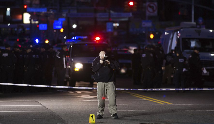 An investigator takes pictures by an evidence marker at the scene where officers shot and killed a man in the Crown Heights section of Brooklyn, Wednesday, April 4, 2018, in New York, as they responded to reports of a man threatening people with a gun. (AP Photo/Kevin Hagen)