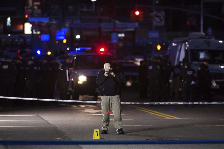 An investigator takes pictures by an evidence marker at the scene where officers shot and killed a man in the Crown Heights section of Brooklyn, Wednesday, April 4, 2018, in New York, as they responded to reports of a man threatening people with a gun. (AP Photo/Kevin Hagen)