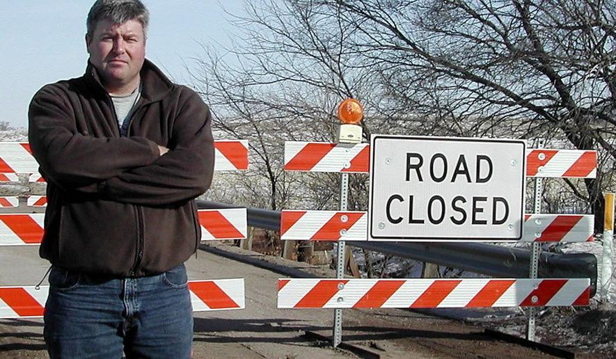 In this undated photo, Saunders County, Neb., Highway Superintendent Steve Mika poses in front of a closed bridge along County Road I, between County Roads 19 and 20. The eastern Nebraska county is nearly caught up on its bridge repair work spanning the last decade. (The Tribune via AP)