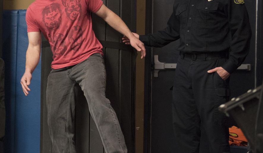 In this March 2018 photo, volunteer Paul Foelber loses his balance as Officer 1st Class Sean Geiser stands watch in case he falls during a sobriety test performed by recruits during a DUI enforcement training session in Frederick, Md. Recruits get hands-on DUI enforcement training thanks to tipsy volunteers. (Graham Cullen/The Frederick News-Post via AP)