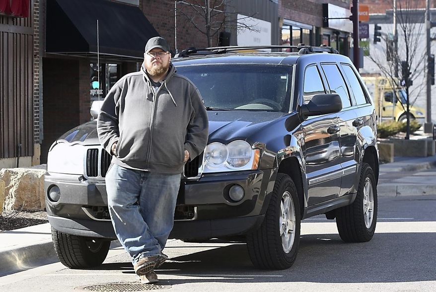In this March 29, 2018, photo, Kevin Webster of Night Owl Sober Driving Service stands near his vehicle in downtown Mankato, Minn. Webster and his partner Ryan Hood drive people home in their vehicle when they've had too much to drink. (Pat Christman/The Free Press via AP)