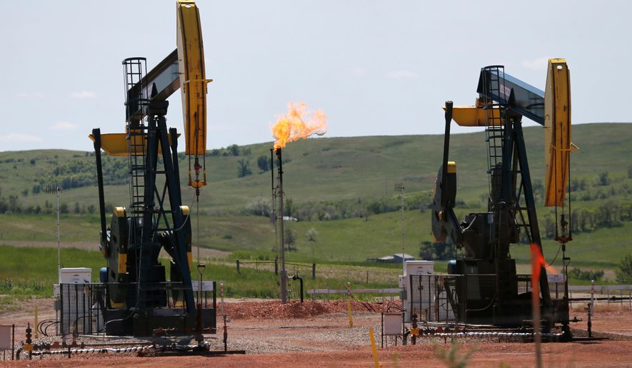 FILE -In this June 12, 2014, file photo, oil pumps and natural gas burn off in Watford City, N.D. An on-again, off-again effort to restrict harmful methane emissions on federal lands is off _ again. A federal judge in Wyoming has halted the clean-air rule indefinitely. (AP Photo/Charles Rex Arbogast, File)