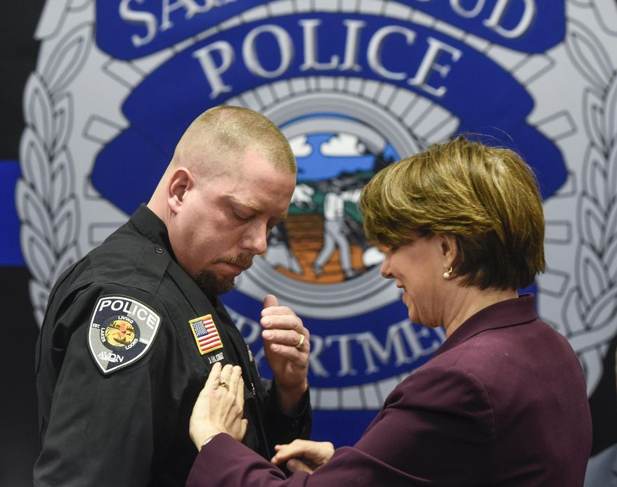 U.S. Sen. Amy Klobuchar presents officer Jason Falconer with the Congressional Badge of Bravery Award during a ceremony Thursday, April 5, 2018, at the St. Cloud Police Department in St. Cloud, Minn. (Dave Schwarz/The St. Cloud Times via AP)