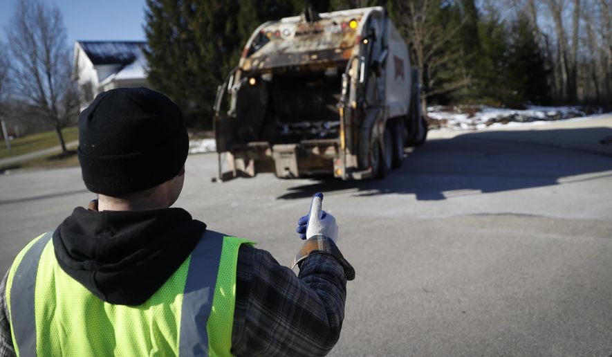 In this March 23, 2018, photo, trainee Brent Cottongin, with Rumpke Waste & Recycling, directs his garbage truck driver as he works a residential route in Beavercreek, Ohio. (AP Photo/John Minchillo) **FILE**