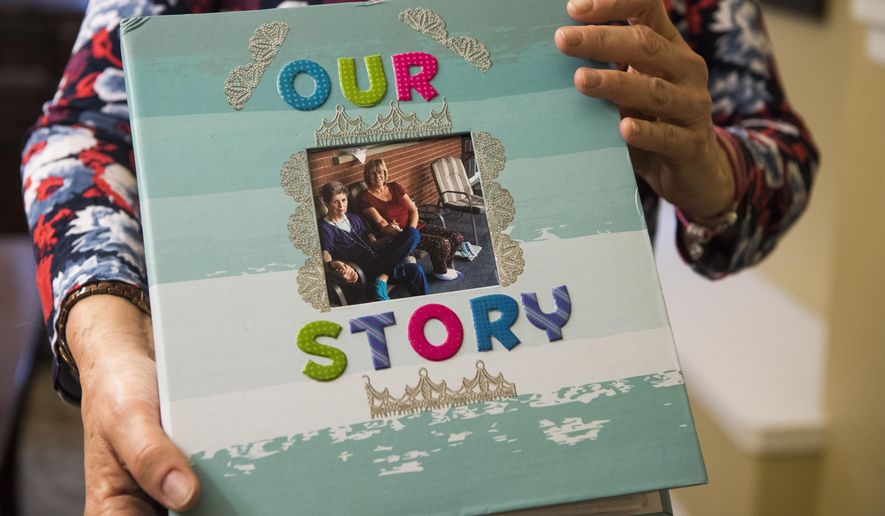 In this March 16, 2018 photo, Kathy Kirkland holds a scrapbook she made from her mother, Joan Harrison, at Brookdale retirement home in Ogden, utah. Harrison gave Kirkland up for adoption 60 years ago, and Kirkland made contact with her last year (James M. Dobson/The Spectrum via AP)