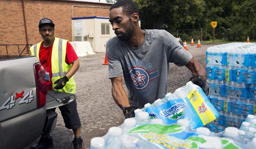In this photo taken Aug. 11, 2017, Shawn Jones, 42, right, and Tony Price, 54, distribute bottled water at a point of distribution in Flint, Mich. Michigan will close the last four locations where Flint, Mich., residents have been getting free bottled water, filters, replacement cartridges and testing kits because the city's water quality has been below federal action levels for lead for nearly two years. (Terray Sylveste /The Flint Journal-MLive.com via AP)