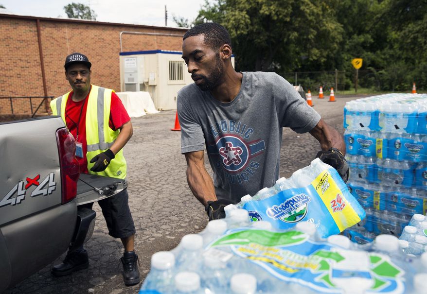 In this photo taken Aug. 11, 2017, Shawn Jones, 42, right, and Tony Price, 54, distribute bottled water at a point of distribution in Flint, Mich. Michigan will close the last four locations where Flint, Mich., residents have been getting free bottled water, filters, replacement cartridges and testing kits because the city's water quality has been below federal action levels for lead for nearly two years. (Terray Sylveste /The Flint Journal-MLive.com via AP)