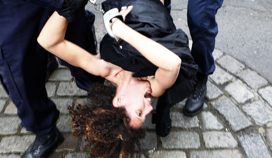 FILE - In a Tuesday, Feb. 10, 2015 file photo, a Femen activist is taken away by police officers as she protests in front of the Lille courthouse in Lille, northern France, where Dominique Strauss-Kahn goes on trial for sex charges in France. The controversial group that seeks to fight patriarchy claimed responsibility for a topless protest Monday, April 9, 2018, at the start of Bill Cosby’s sexual assault retrial in Pennsylvania.  (AP Photo/Michel Spingler, File)