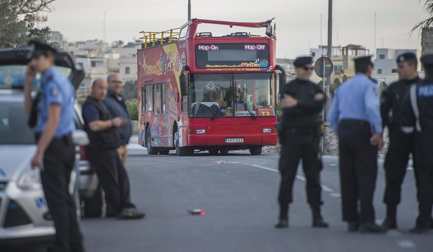 Police officers stand next to an open-top double-decker tourist bus that slammed into a low-hanging tree branch killing two people and injuring 45 others, including a dozen children, in the tourists destination of Zurrieq, near Valletta, Malta, Monday, April 9, 2018. Health Minister Chris Fearne said most of the passengers hailed from Belgium or Britain, though police said the seriously injured also included a German and Italian. (AP Photo/Rene Rossignaud)