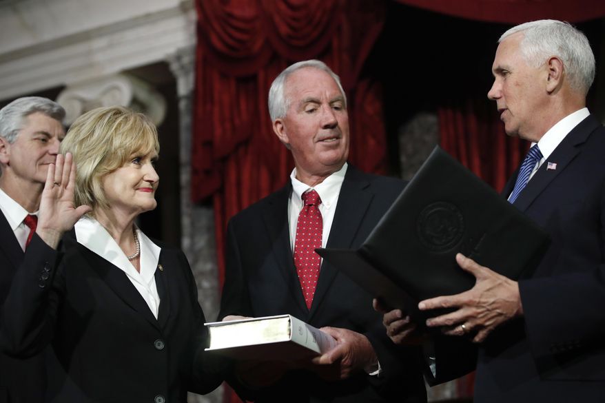 Mississippi Republican Cindy Hyde-Smith, left, is welcomed as the newest member of the U.S. Senate by Vice President Mike Pence, right, as she is joined by her husband, Michael Smith, center, and Mississippi Gov. Phil Bryant, far left, during a ceremonial swearing-in at the Old Senate Chamber, Monday, April 9, 2018, in the Capitol in Washington. She was appointed by Mississippi Gov. Bryant to succeed Sen. Thad Cochran, R-Miss., who resigned in April for health reasons. (AP Photo/Jacquelyn Martin)