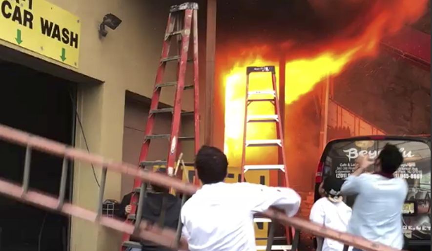 In this Monday, April 9, 2018 photo, girls flee a second-story dance studio onto a balcony as a roaring fire engulfs their building in Edgewater, N.J. About 15 girls were treated for minor injuries, Mayor Michel Joseph McPartland said. (Ilker Kesiktas via AP)
