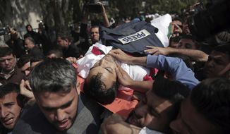 Mourners carry the body of Palestinian cameraman who was shot and killed, Friday by Israeli troops while covering a protest at the Gaza Strip&#39;s border with Israel, during his funeral in Gaza City, Saturday, April 7, 2018. (AP Photo/ Khalil Hamra)