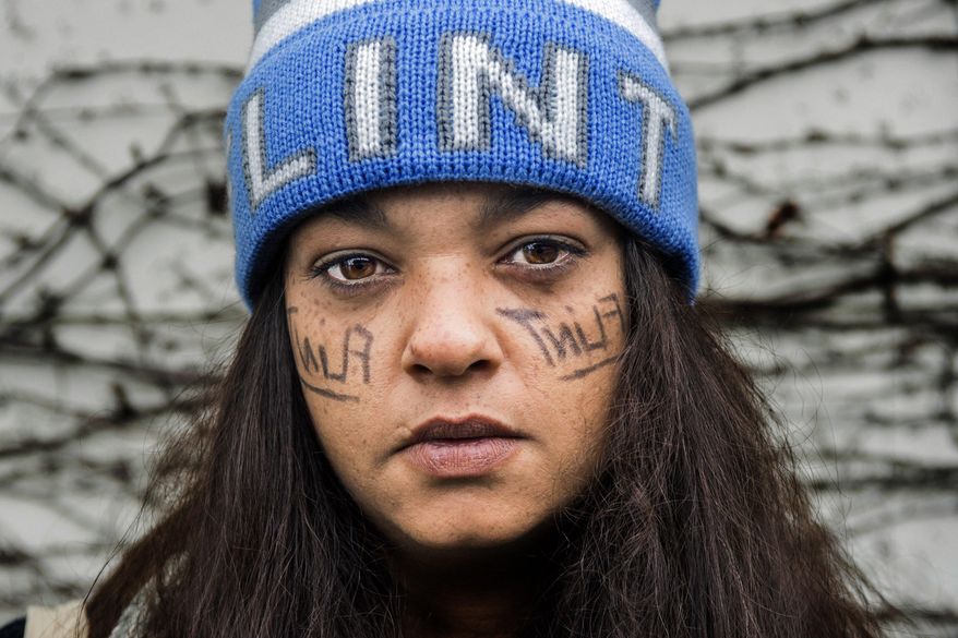 Flint resident JoJo Freeman wears the words Flint backwards on her face as eye black, as she loads onto the bus to protest at the state capitol on Wednesday, April 11, 2018 at Salem Lutheran Church in Flint. A group of more than 50 Flint residents joined to protest less than 24 hours after the closure of the city's last four water distribution sites on Tuesday. (Jake May/The Flint Journal-MLive.com via AP)