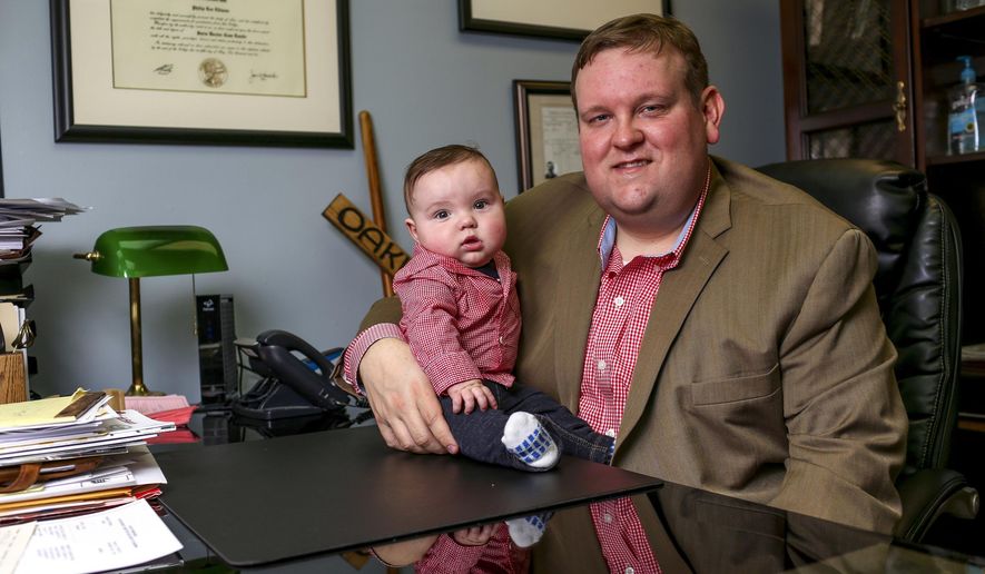 In this March 23, 2018 photo, Philip Ellison poses for a photo with Patton Ellison at his firm Outside Legal Counsel in Hemlock, Mich. If you were born in Michigan in July 1984 or later, you may be among more than five million people whose blood is being held by the state of Michigan, some of which may be used in medical research. Philip Ellison is suing the state on behalf of a group of parents who say the state did not obtain proper consent for their newborns' blood to be drawn or stored. (Henry Taylor/The Flint Journal-MLive.com via AP)
