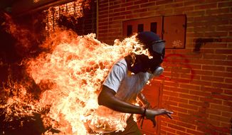In this image released by World Press Photo Thursday April 12, 2018, which won the World Press Photo of the Year and the first prize Spot News singles category, titled &amp;quot;Venezuela Crisis&amp;quot; by Ronaldo Schemidt for Agence France-Presse shows José Víctor Salazar Balza (28) catching fire amid violent clashes with riot police during a protest against President Nicolas Maduro, in Caracas, Venezuela, May 3, 2017. (Ronaldo Schemidt, AFP, World Press Photo via AP)