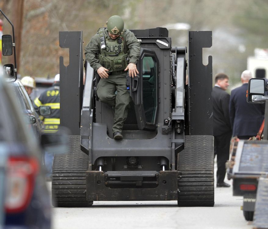 Cape Cod SWAT team members bring in the Rook tactical solutions vehicle to the scene of a shooting in Barnstable, Mass., Thursday, April 12, 2018. A K-9 officer has been shot and killed while serving a warrant at a Massachusetts home and a suspect has been taken into custody. (Ron Schloerb/The Cape Cod Times via AP)