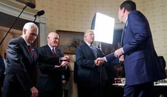 FILE - In this this Jan. 22, 2017, file photo, Vice President Mike Pence, left, and Secret Service Director Joseph Clancy stand as President Donald Trump shakes hands with then-FBI Director James Comey during a reception for inaugural law enforcement officers and first responders in the Blue Room of the White House in Washington. Comey is blasting Trump as “unethical and untethered to truth,” and says Trump’s leadership of the country is “ego driven and about personal loyalty.” Comey’s comments come in a new book in which he casts Trump as a mafia boss-like figure who sought to blur the line between law enforcement and politics.  (AP Photo/Alex Brandon, File)