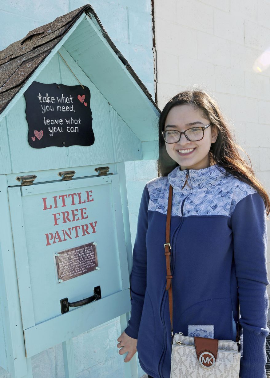 In this April 3, 2018 photo, Hutchison High School student body president Michelle Kougl poses next to the Little Free Pantry outside the Fairbanks Native Association Community Services building in Fairbanks, Alaska. Little Free Pantry is a nationwide movement based on the Little Free Library kiosks. But instead of books, Little Free Pantry is a place where people in need can find basic staples, and people with extra can share. (Eric Engman/Fairbanks Daily News-Miner via AP)